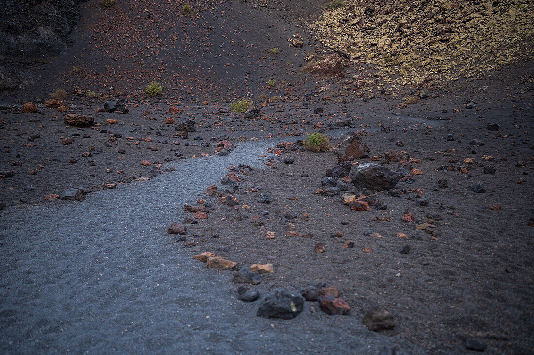 Volcan del Cuervo (Krähenvulkan), ein Krater, der über einen Rundweg in einer kargen, felsigen Landschaft erkundet wird