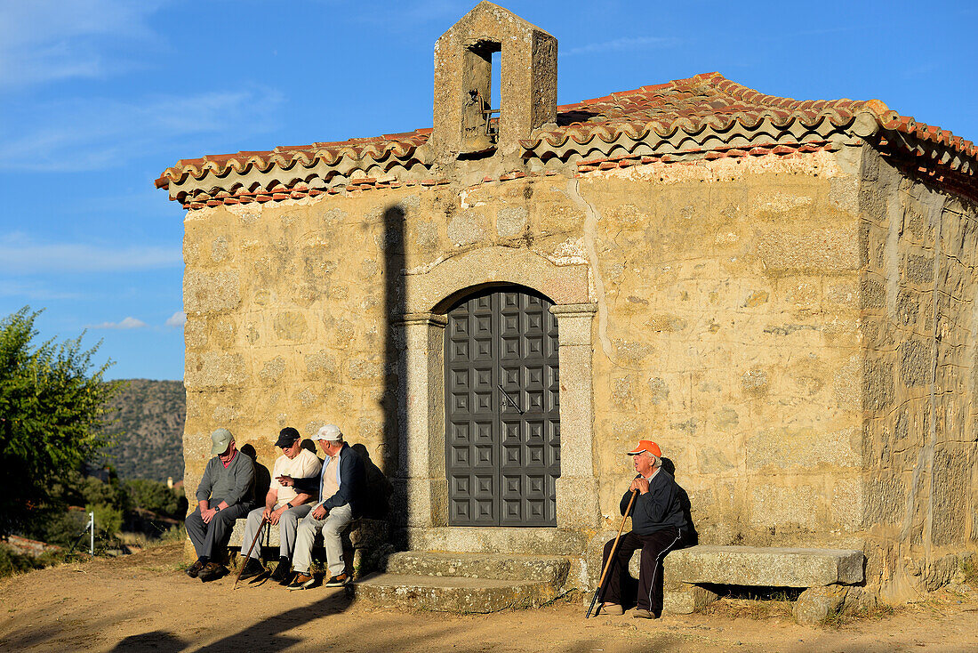 Vier Rentner sitzen auf den Steinbänken der Einsiedelei El Consuelo in der Stadt Santa Cruz de Pinares, Provinz Ávila