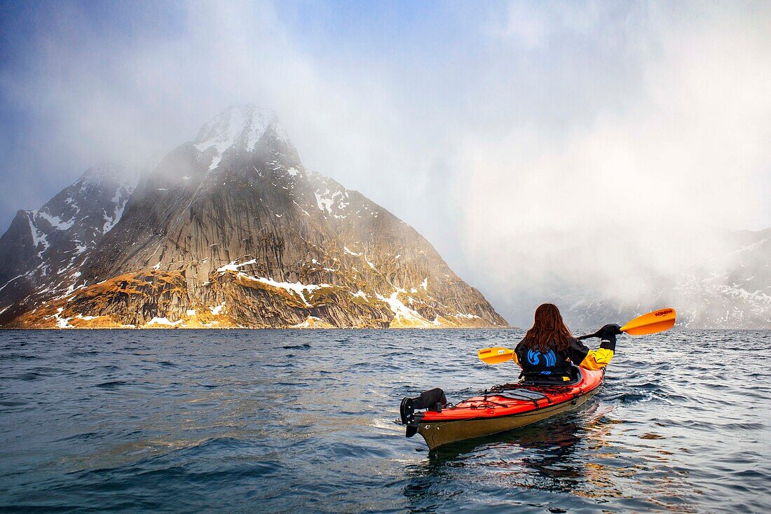 Kajakfahren in Reine, Moskenes, Insel Moskenesøya, Lofoten-Inseln, Norwegen. Landschaft mit dem Berg Olstinden Peak