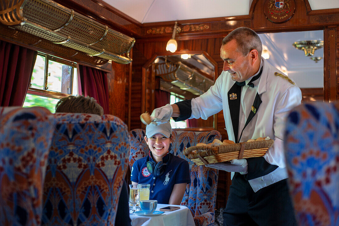 A waiter serves the lunch inside the restaurant wagon of the train Belmond British Pullman luxury train stoped at Folkestone train station railway station in England.