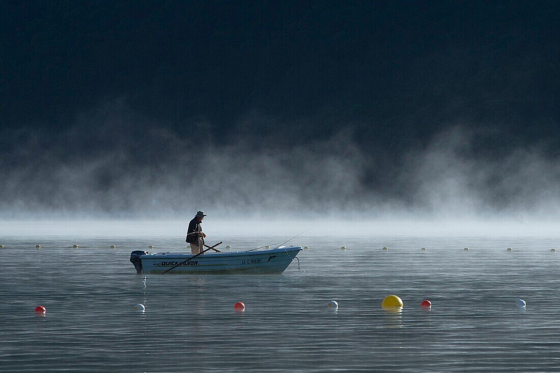 France, Haute Savoie, Lake Annecy, pecheur on a boat in the morning(early) mists off the beach of Doussard