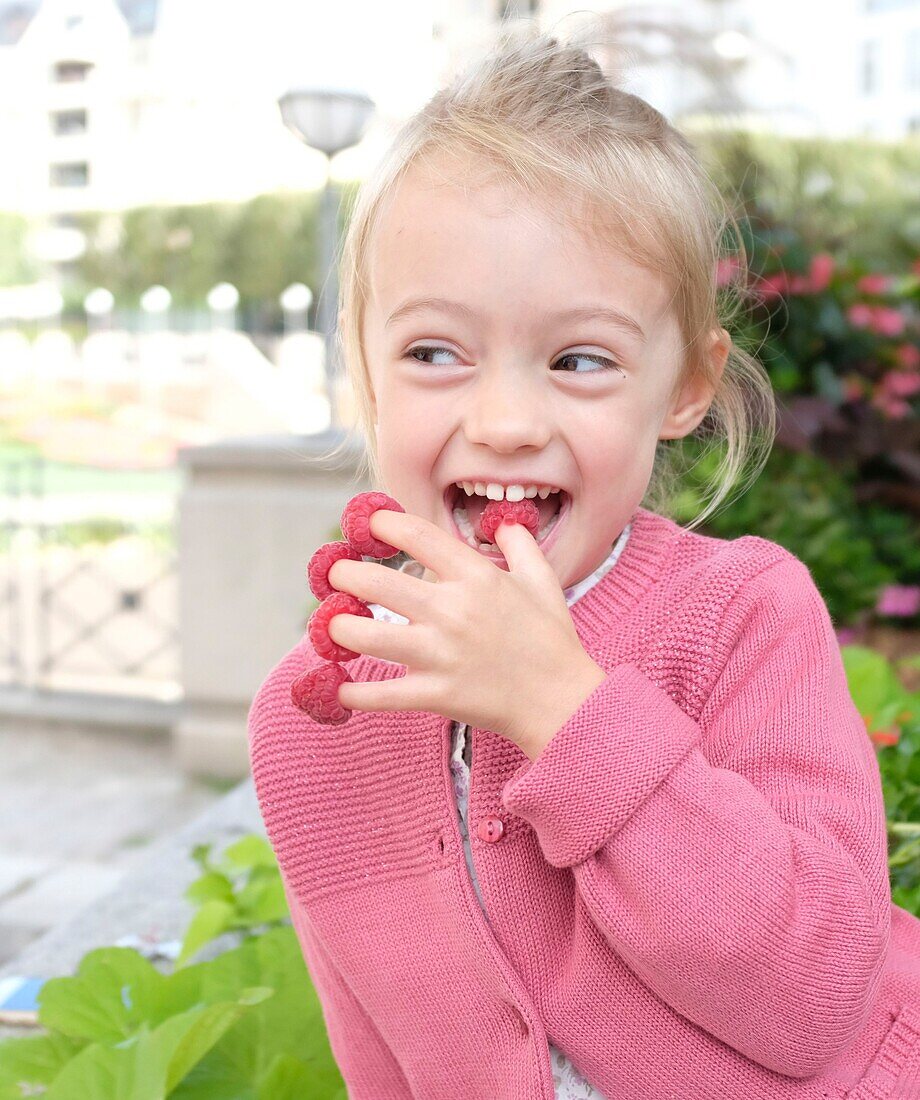 France, Val de Marne, Charenton le Pont, girl playing with raspberries