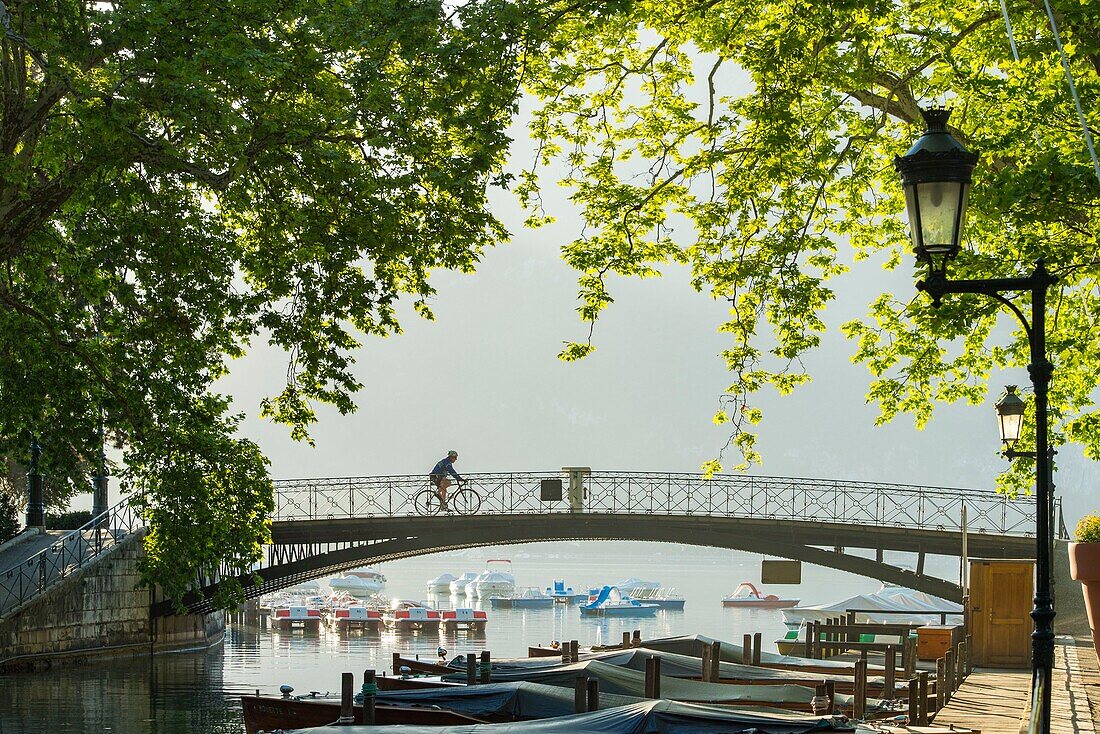 France, Haute Savoie, Annecy, cyclist on the bridge of the Loves at the sunrise and the beginning of the canal du Vasse