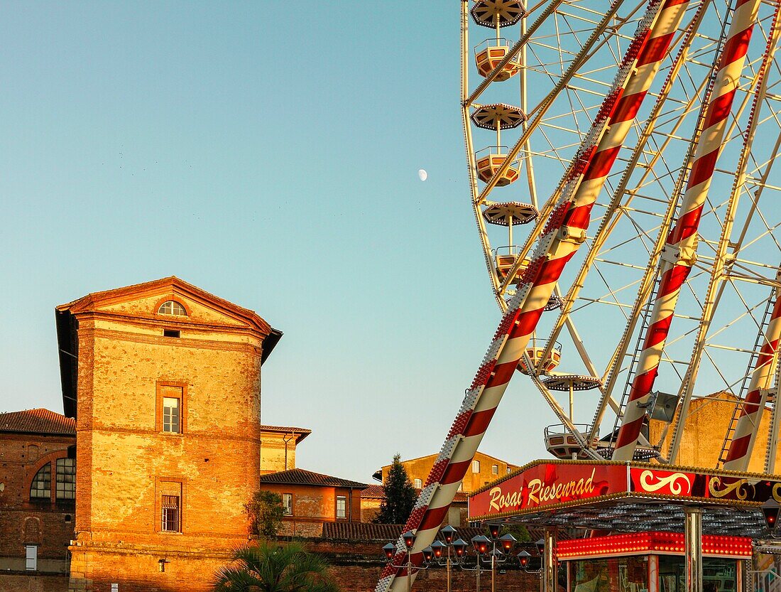 France, Haute-Garonne, Toulouse, listed at Great Tourist Sites in Midi-Pyrenees, St; Cyprien, view of the Ferris wheel and a stone building at sunset