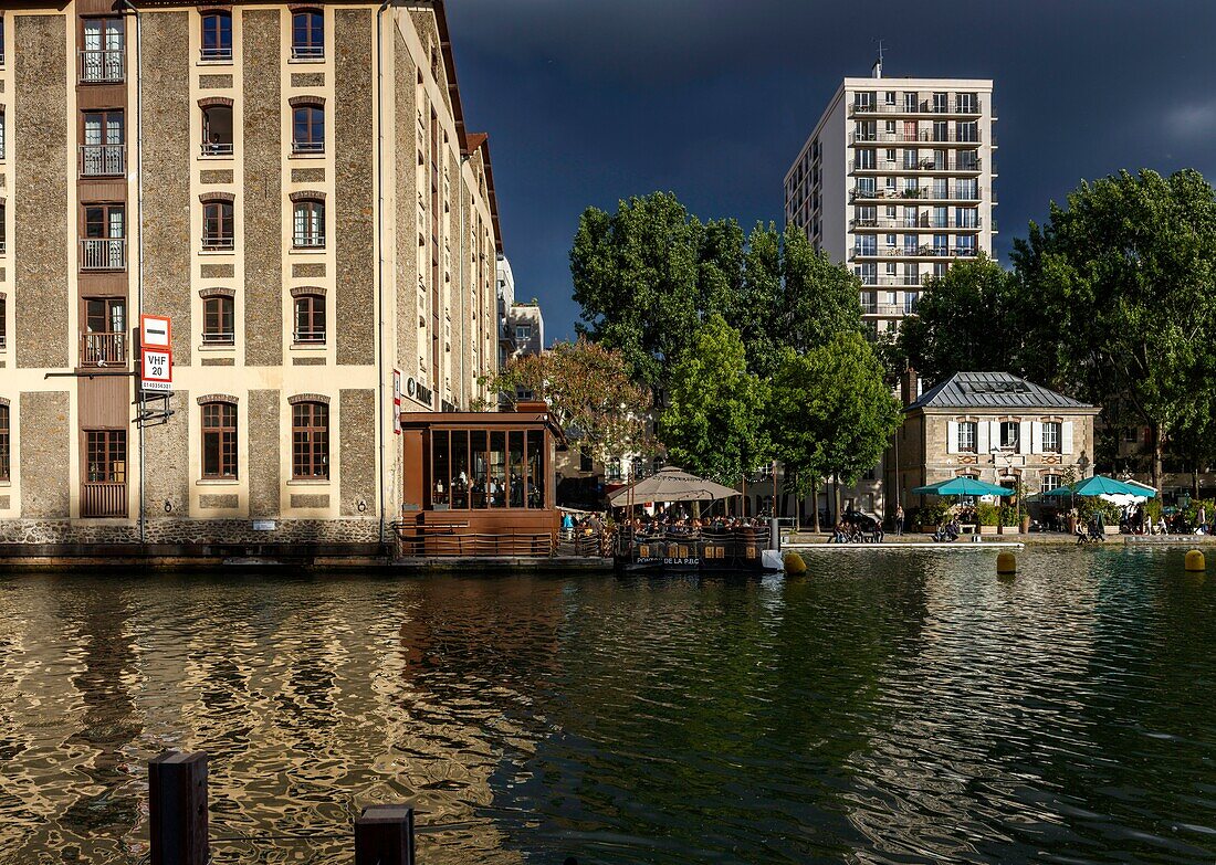 Frankreich, Paris, La Villette, Villette-Kanal, Blick auf die Straßenanimation der Quais des Kanals von La Villette unter einem Gewitterhimmel