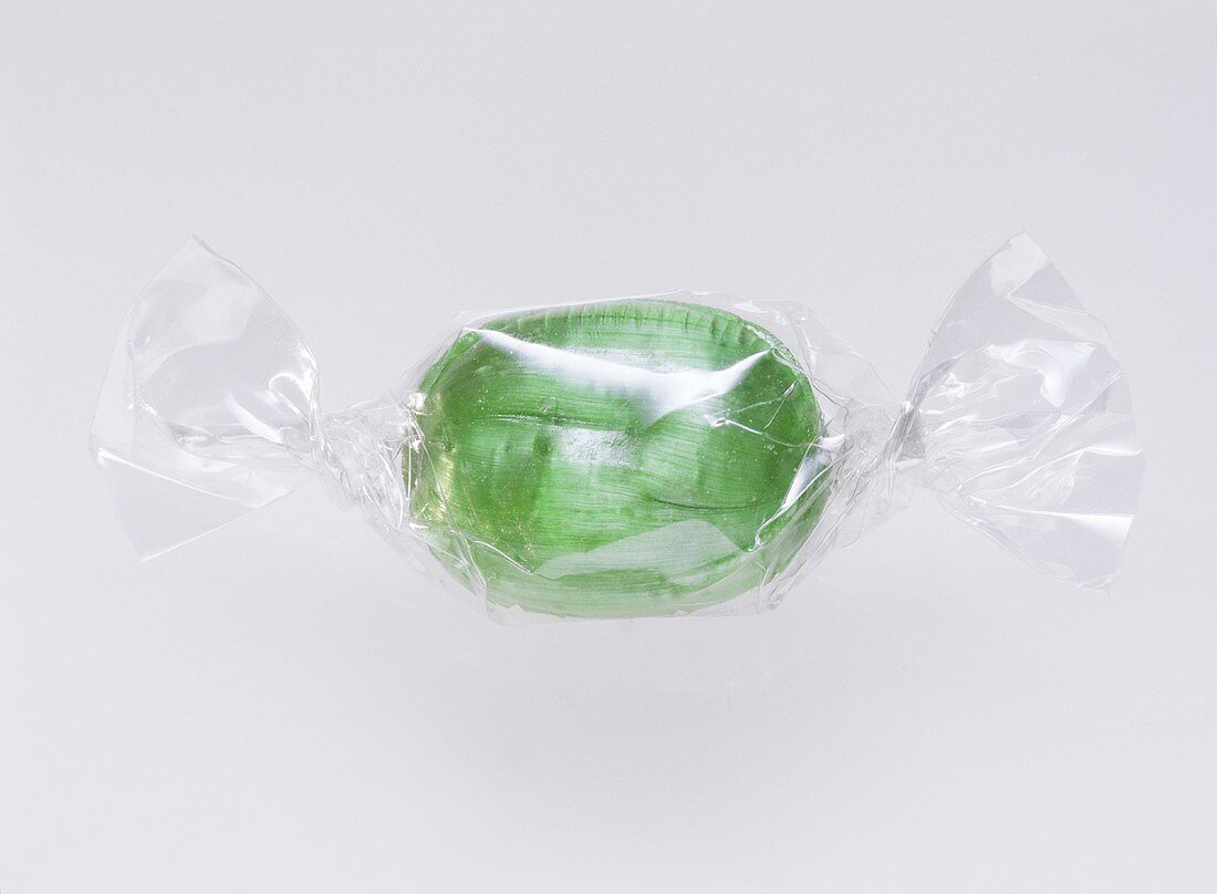 Ein grünes Bonbon in Klarsichtfolie