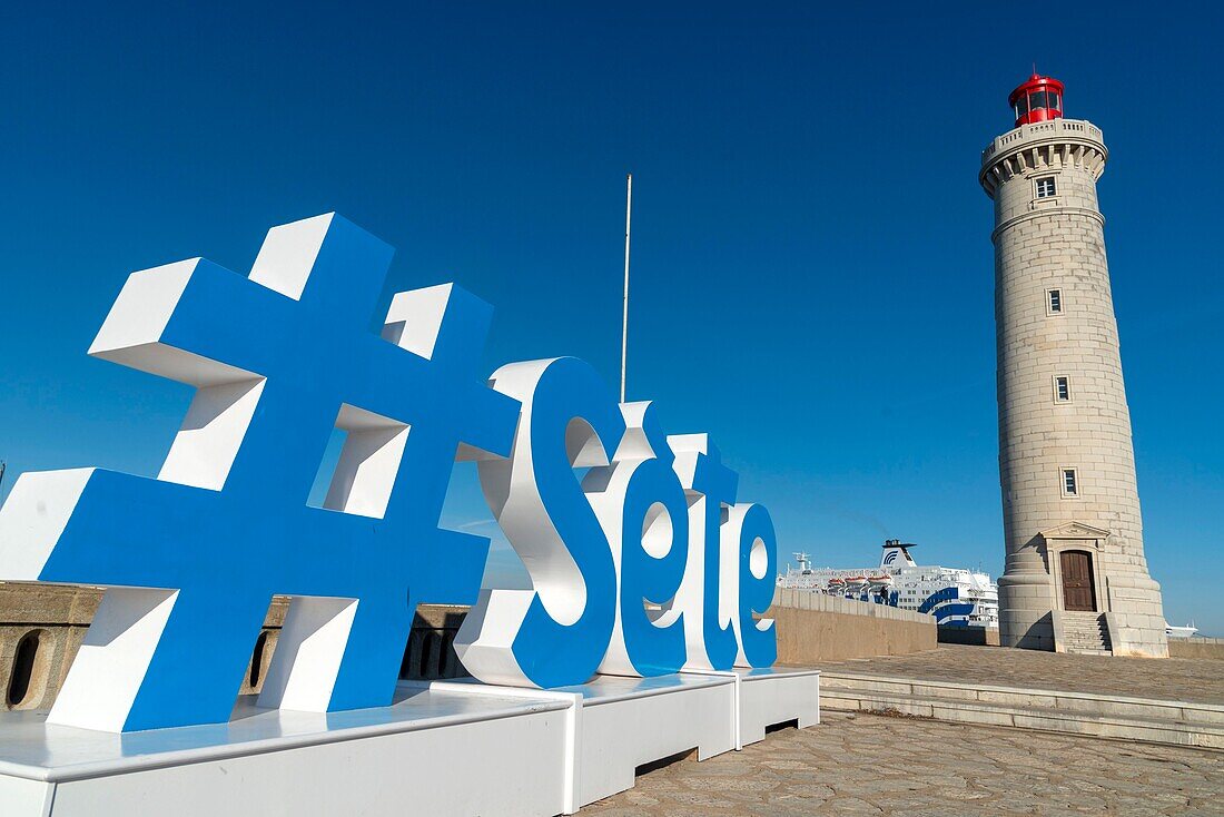 France, Herault, Sete, Saint-Louis Mole, sculpture of hashtag representing the city of Sete with a lighthouse in the background