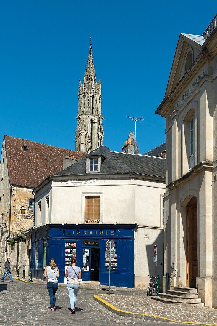 France, Oise, Senlis, women walking on street paved with a bookshop and a church in the background