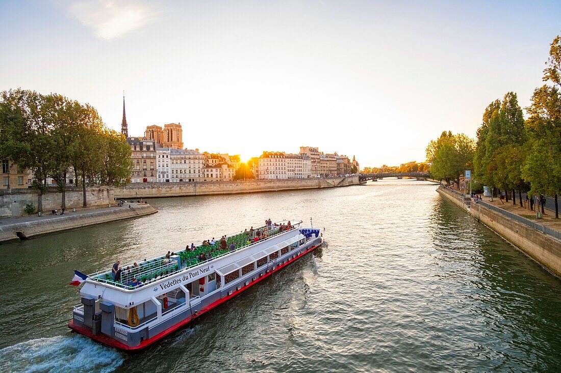 France, Paris, Seine river banks listed as World Heritage by UNESCO, a fly boat passes in front of Saint Louis Island and Notre Dame cathedral