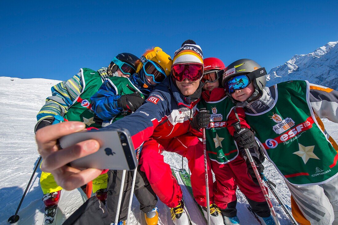 Frankreich, Haute Savoie, Massiv des Mont Blanc, die Contamines Montjoie, die Kinder im Skikurs mit Skilehrer ESF, der ein Foto der Gruppe mit Tontelefonen macht