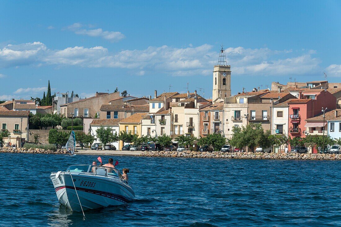 Frankreich, Herault, Bouzigues, Motorboot mit einem Dorf im Hintergrund auf der Lagune von Thau