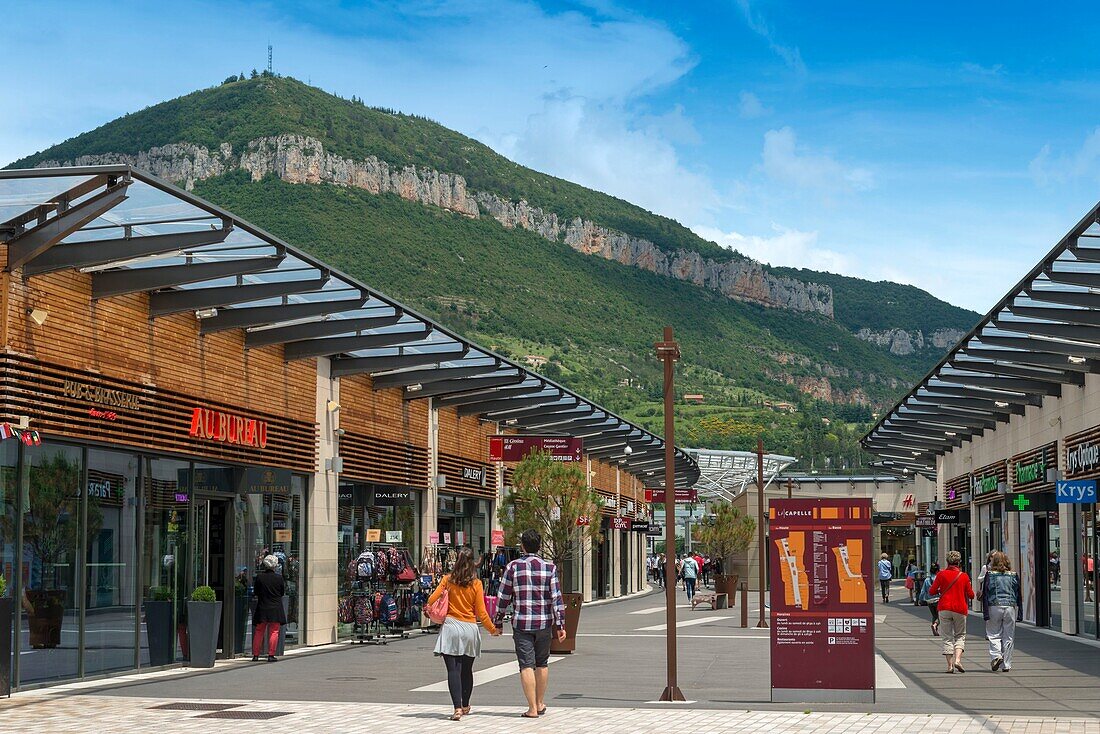 Frankreich, Aveyron, Millau, Place de la Fraternité, Einkaufszentrum Capelle mit einem Berg im Hintergrund, Spaziergänger kommen und gehen