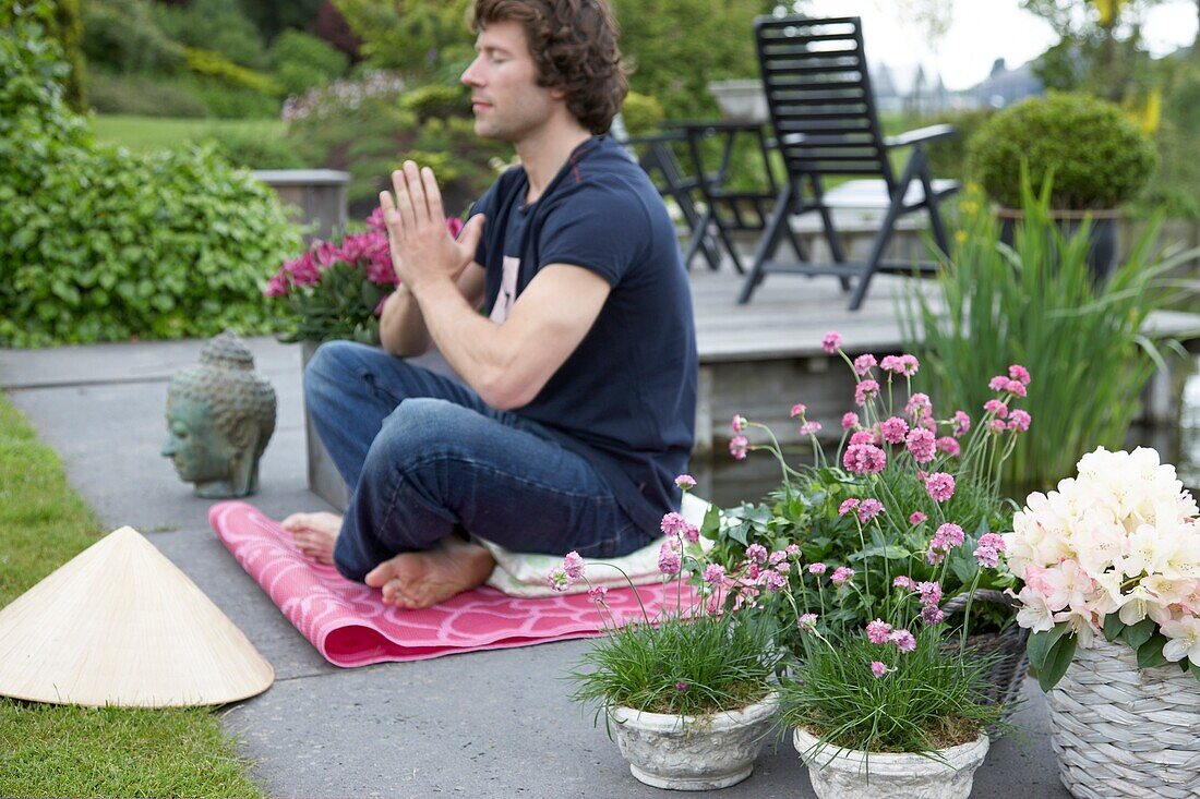 Mann meditiert im Garten