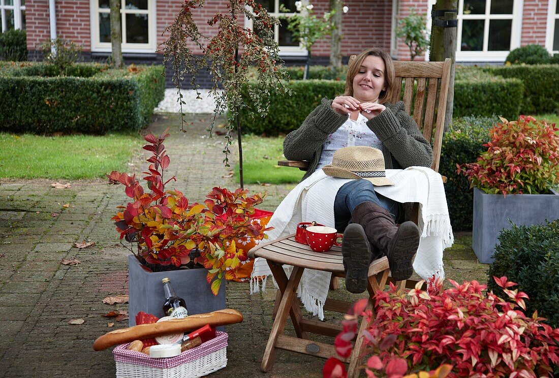 Frau auf Herbstterrasse sitzend