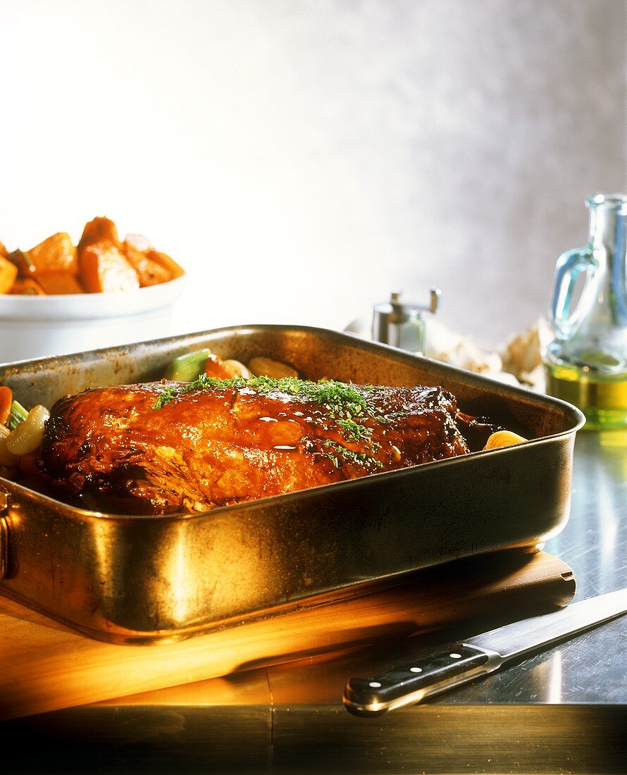 Roast pork with herbs in roasting tin on kitchen table