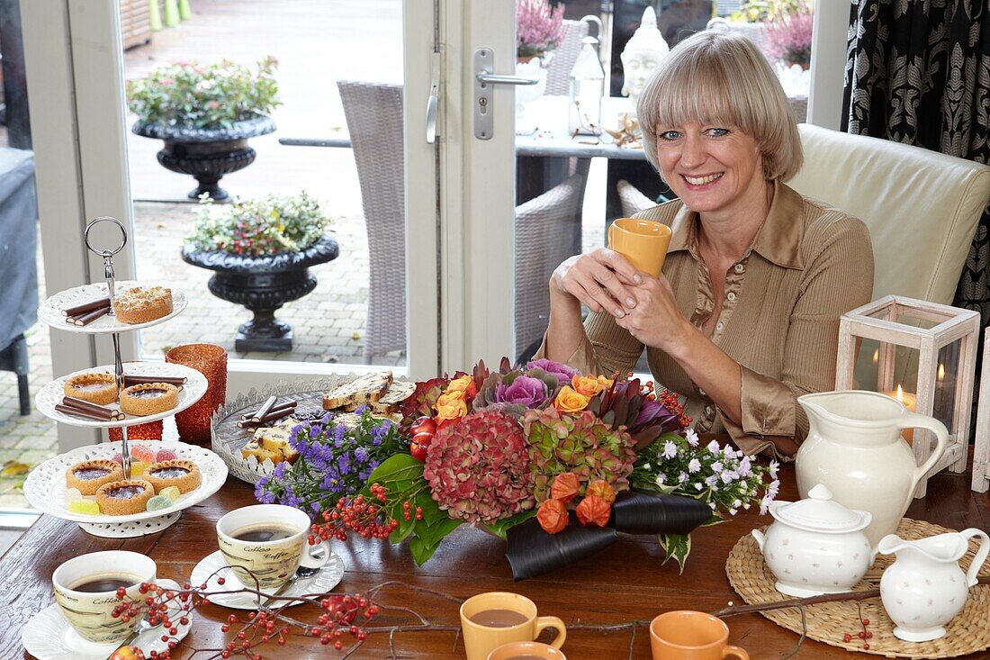 Florist sitzend bei Herbstgesteck