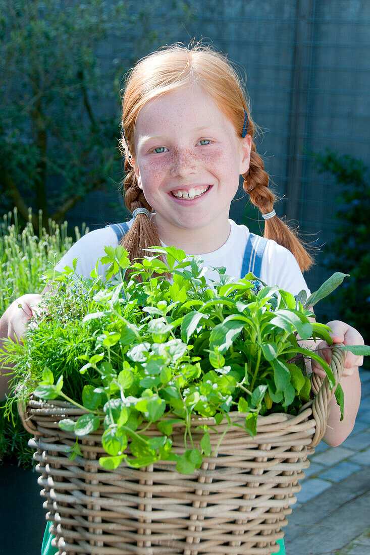 Girl holding basket with mixed herbs