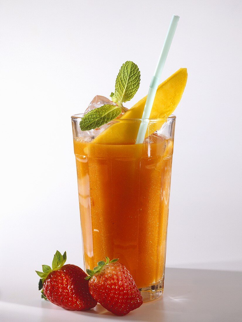 Mango & strawberry drink in glass with straw; strawberries