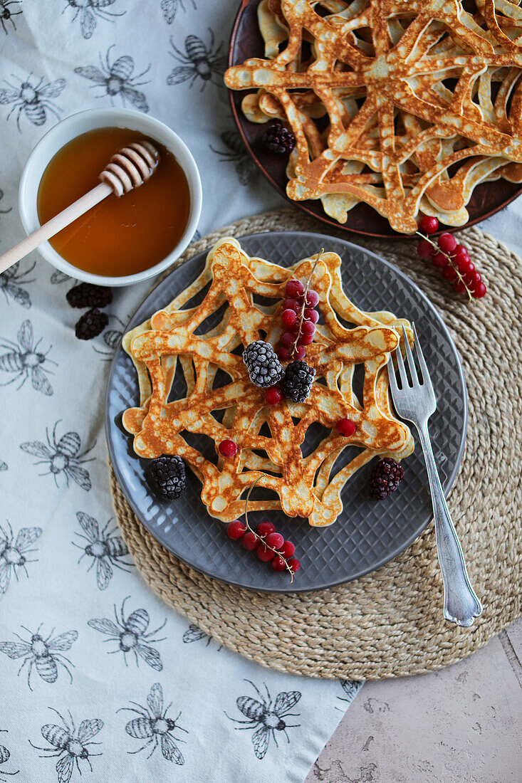 Spider web pancakes with berries and maple syrup