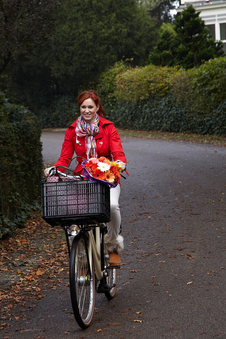 Woman riding bicycle holding flowers