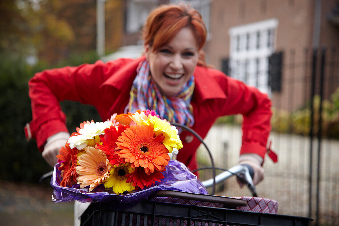 Woman riding bicycle holding flowers