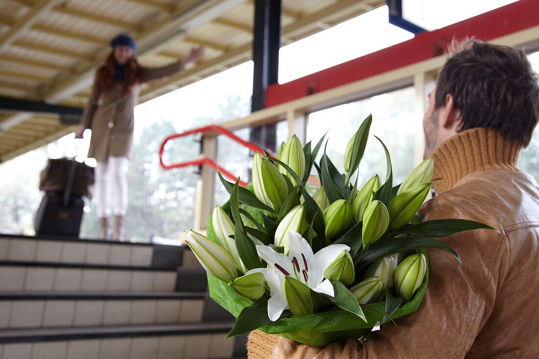 Mann begrüßt Frau mit Blumen