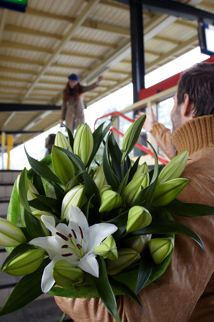 Mann begrüßt Frau mit Blumen