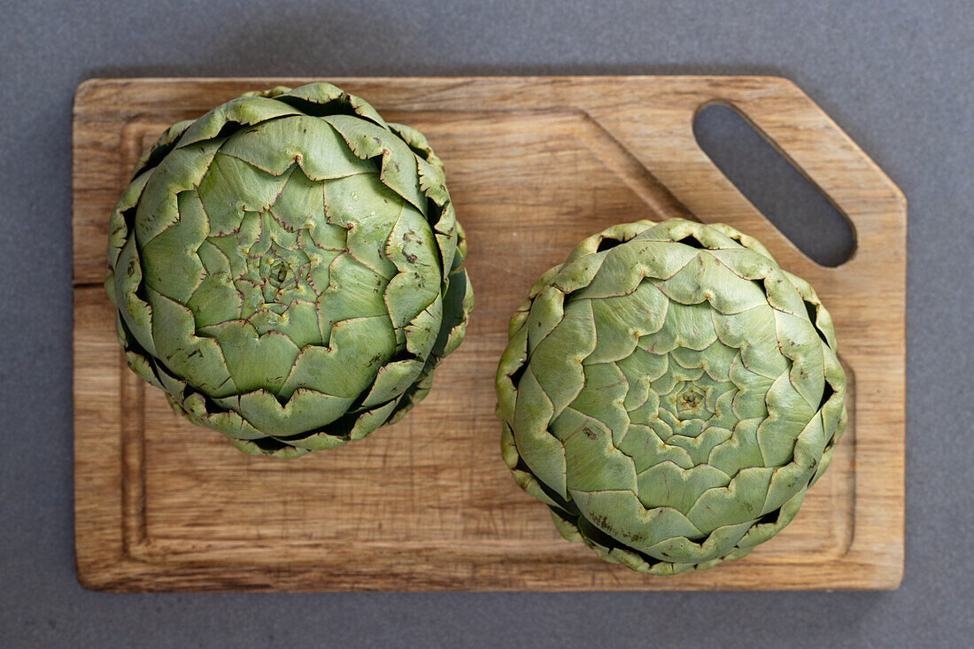 Two fresh artichokes on a wooden board