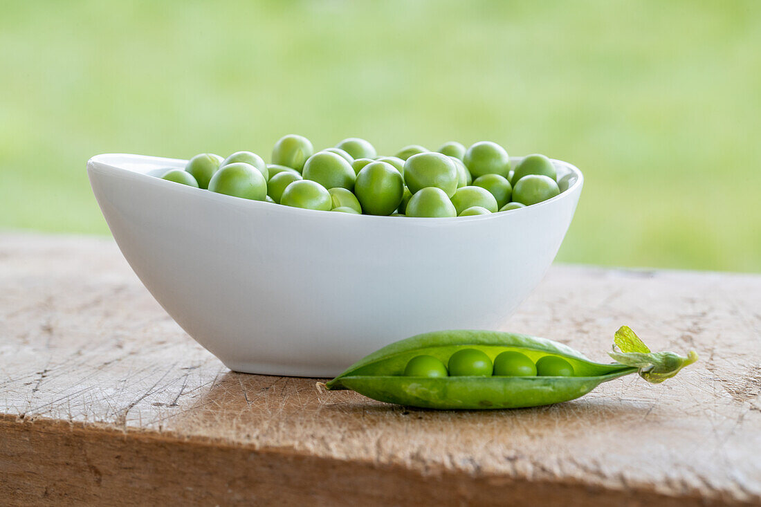 Bowl of fresh peas on a wooden table