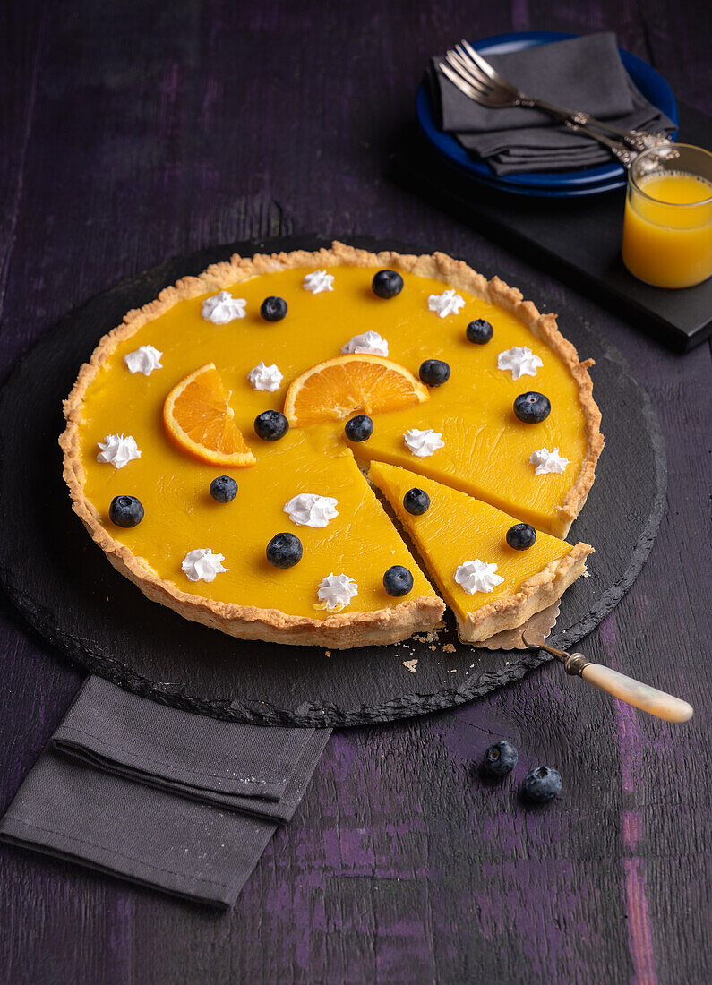 Vegan orange tart with dots of cream and blueberries