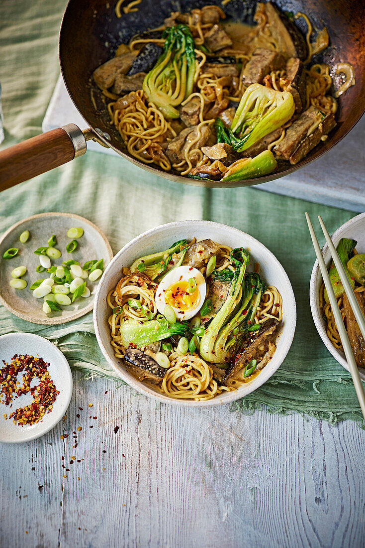 Aubergine and peanut stir fry with egg, noodles and pak choi