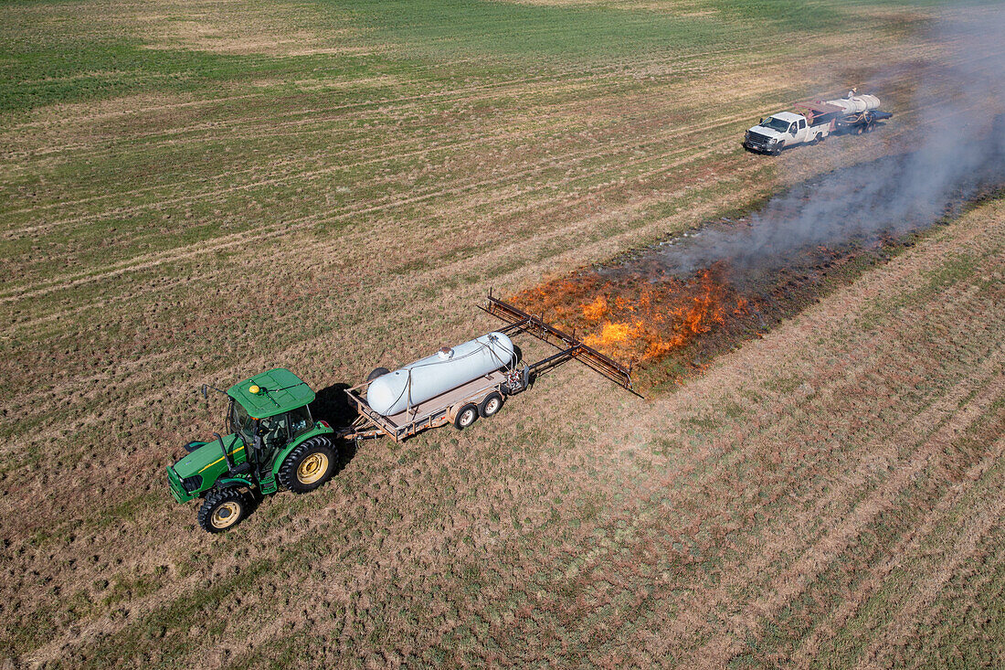 Aerial view of tractor pulling propane burner in hay field