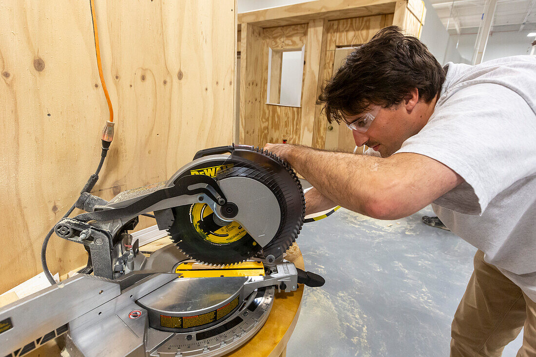 Apprentice carpenter using mitre saw