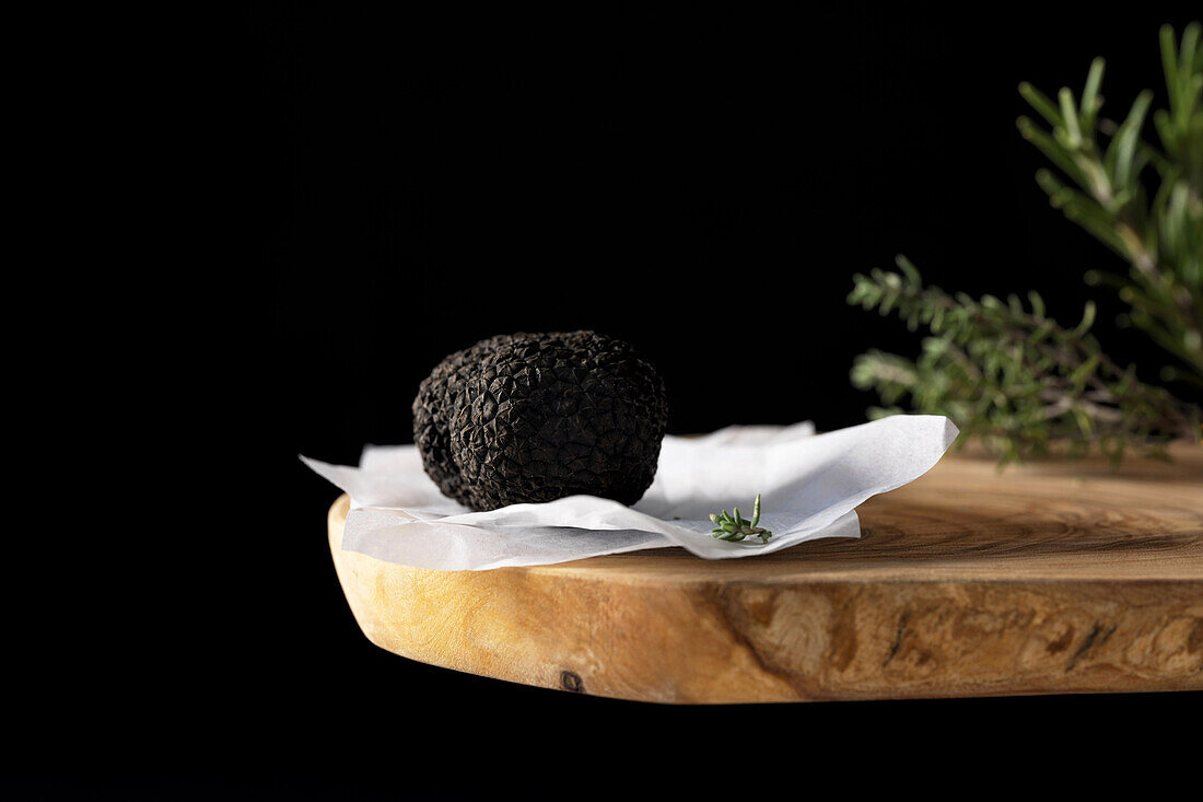 A whole black winter truffle and herbs