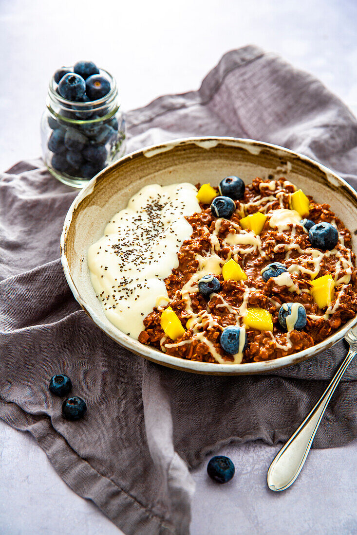Porridge mit Joghurt, Heidelbeeren, Mango, Chia und Mandelmus