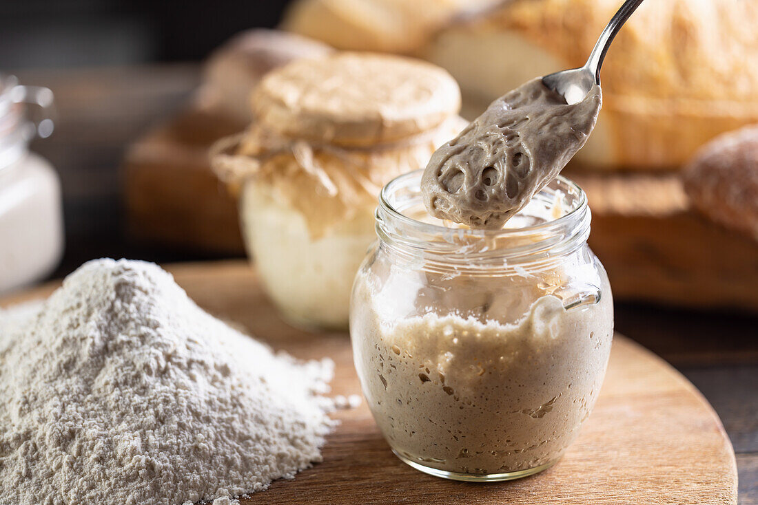 Matured rye sourdough in a jar with flour on a chopping board