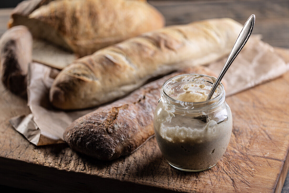 Rye sourdough in a jar and fresh bread on a chopping board