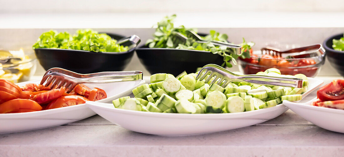 Frisches Gemüse, Gurken, Tomaten und Salat in Schüsseln auf Buffett im Restaurant