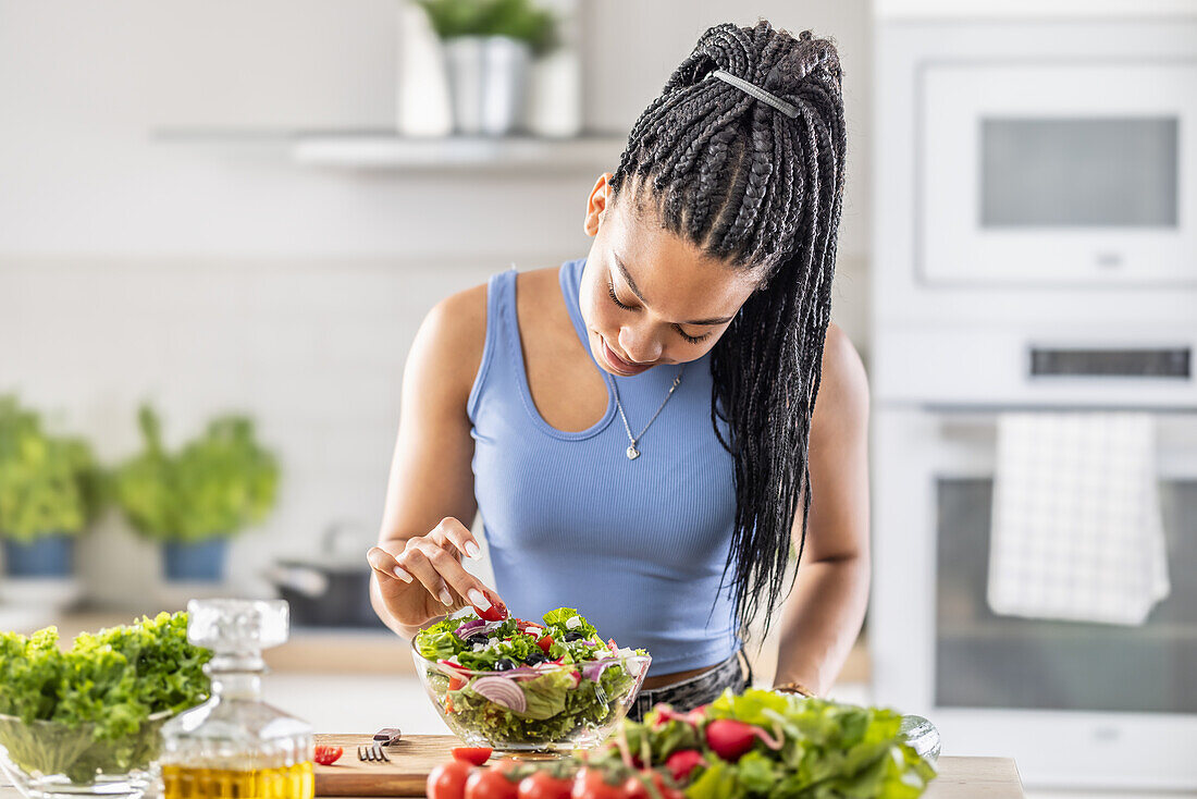 Young African-American woman prepares healthy salad