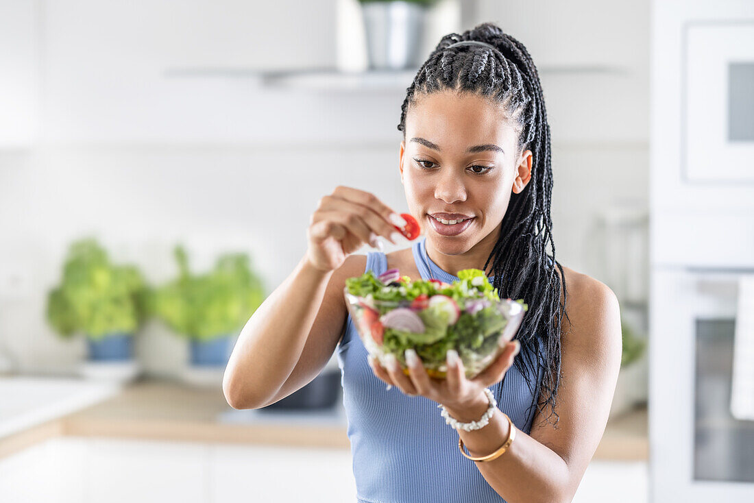 Junge Afroamerikanerin bereitet gesunden Salat zu