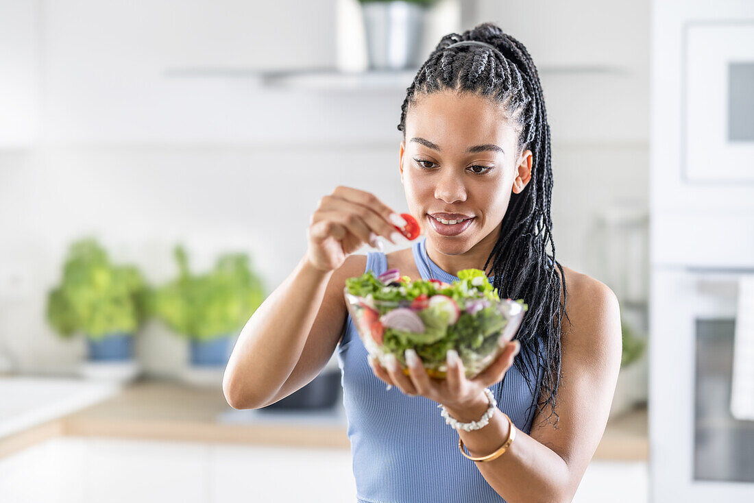 Young African-American woman prepares healthy salad