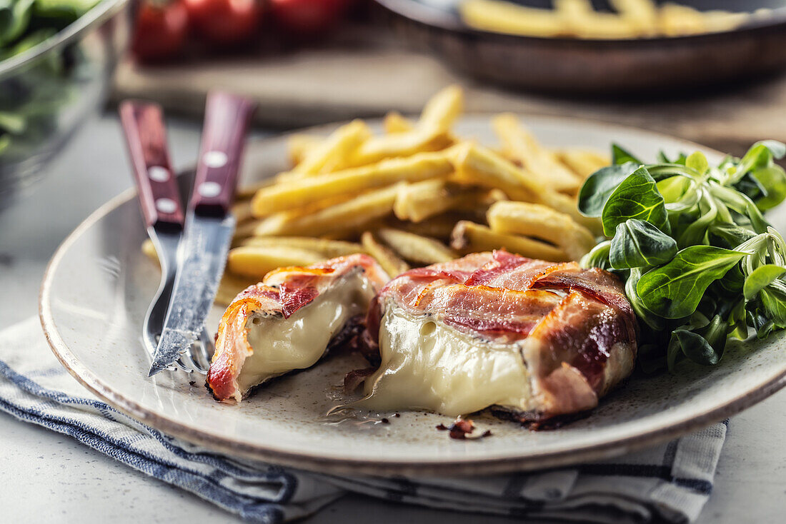 Fried brie cheese wrapped in bacon with chips and leaf salad