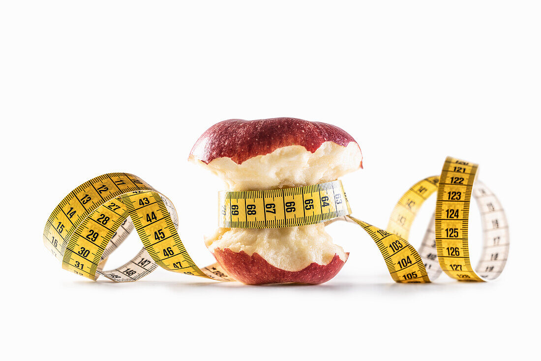 Red apple wrapped with measuring tape on a white background
