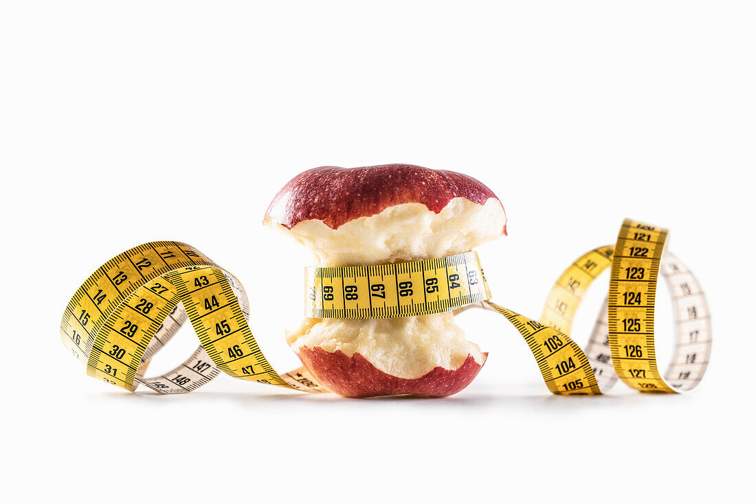 Roter Apfel mit Maßband umwickelt auf weißem Hintergrund