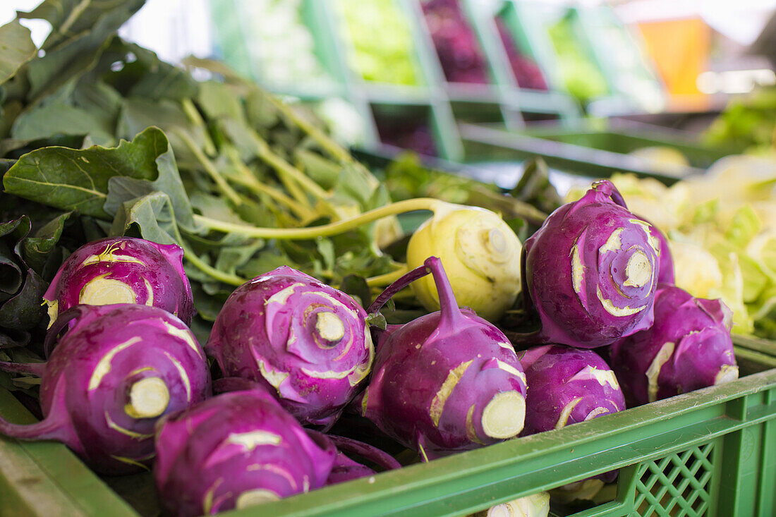 A box of green and purple kohlrabi at the market
