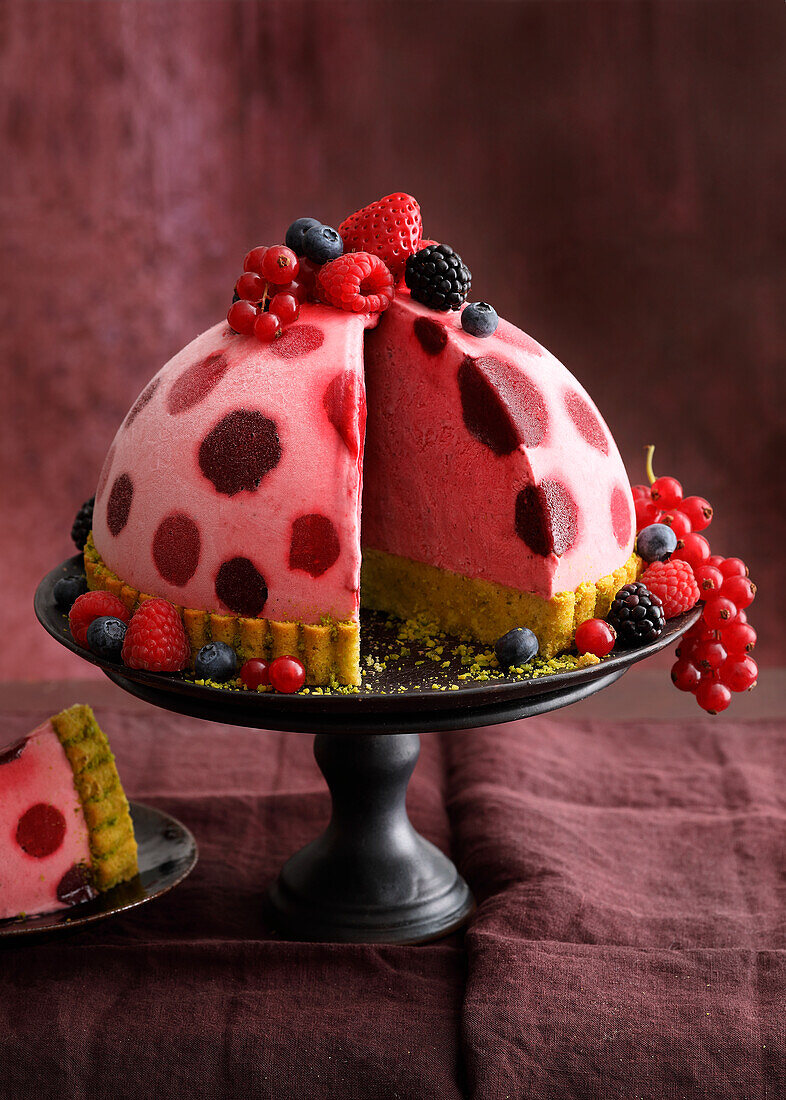 Summer berry ice cream bomb on pistachio sponge cake