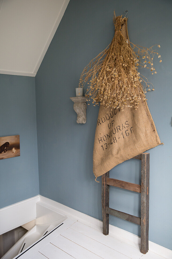 Decorative wall design with dried flowers, ladder and jute sack