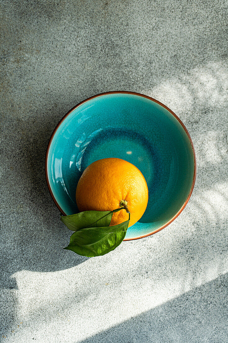 Orange with leaves in a ceramic bowl