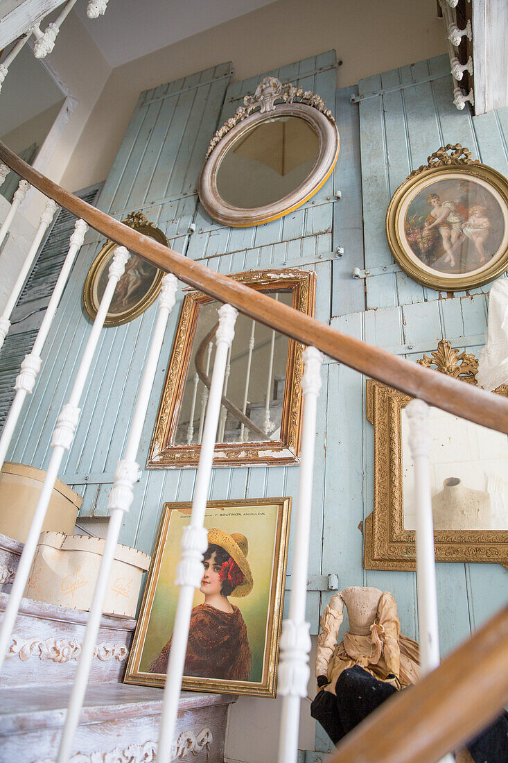 Vintage gallery wall with framed portraits and mirrors in the staircase