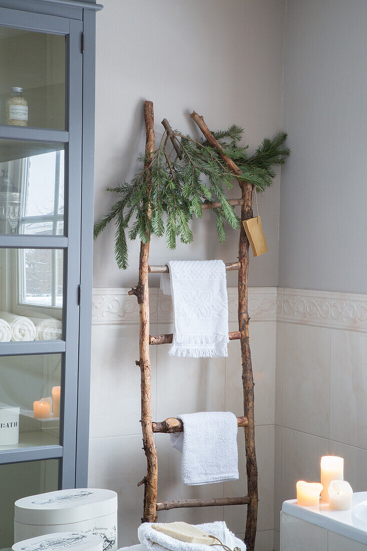 Rustikale Holzleiter mit Tannenzweigen und Handtüchern im Badezimmer